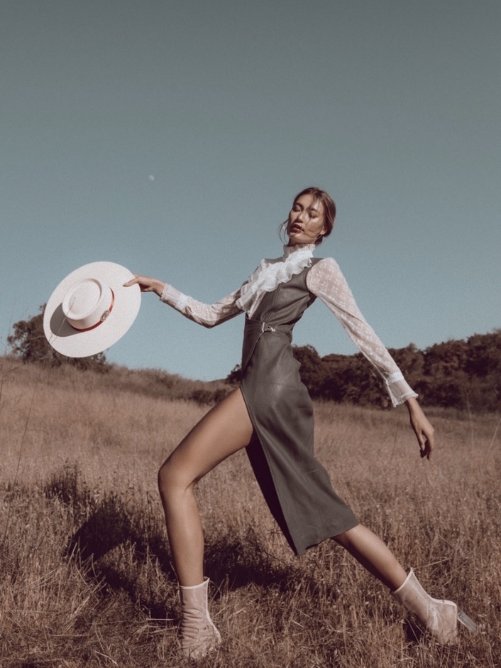 Fashion editorial in a sculptural dress walking through a field